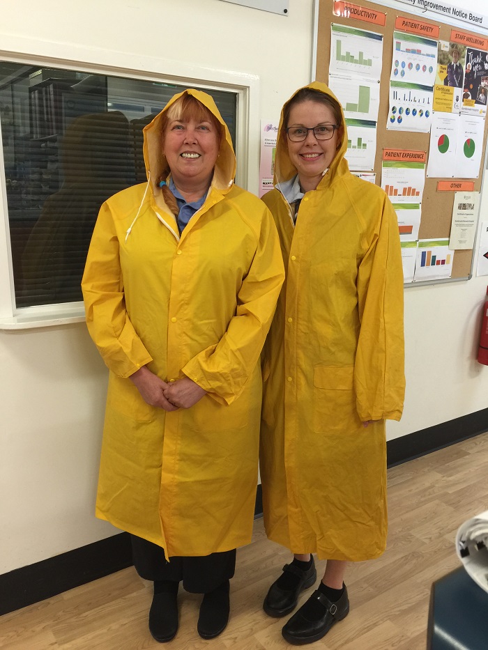 two nurses wear yellow raincoats