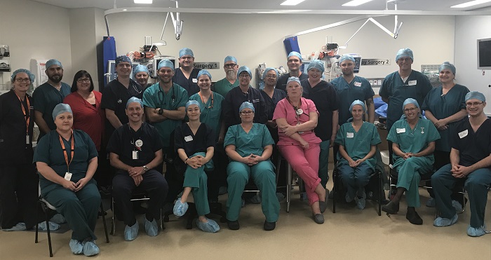 group of hospital staff and trainers line up for photo in operating theatre